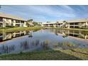 Scenic waterfront community with a serene pond reflecting the surrounding buildings, trees, and clear blue sky at 345 Three Lakes Ln # L, Venice, FL 34285