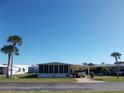 Single-story home with an enclosed sunroom, carport, and palm trees against a clear blue sky at 425 Boxwood Dr, Venice, FL 34285