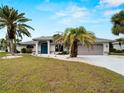 Inviting single-story home with a well-kept lawn and landscaping featuring mature palm trees and a paved driveway at 8 Bunker Ln, Rotonda West, FL 33947
