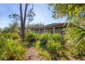 Exterior view showcasing a covered porch surrounded by mature landscaping at 1115 Gladstone Blvd, Englewood, FL 34223