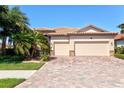 Charming single-story home featuring a red-tiled roof, brick driveway, and lush tropical landscaping at 13240 Amerigo Ln, Venice, FL 34293