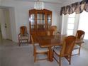 Traditional dining room with wooden table set, china cabinet, and bright natural lighting at 157 Algiers Dr, Venice, FL 34293