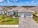 Inviting single-Gathering home featuring well-maintained landscaping, paver driveway, and an attached two-car garage at 18135 Home Run Dr, Venice, FL 34293
