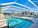 Inviting screened-in pool area featuring a sparkling pool, brick paver deck, and outdoor seating at 2 Windsor Dr, Englewood, FL 34223