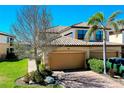 View of home featuring a two-car garage, mature landscaping, and driveway at 20181 Ragazza Cir # 101, Venice, FL 34293