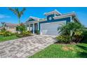 Beautiful light blue home with a paver driveway and vibrant landscaping at 20420 Symphony Pl, Venice, FL 34293