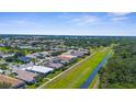 Wide aerial view of a neighborhood featuring homes, manicured lawns, canal, and lush green spaces on a bright sunny day at 213 Venice Palms Blvd, Venice, FL 34292