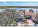 A home with a red tile roof sits next to a lake and other red-tiled homes in a community at 23138 Copperleaf Dr, Venice, FL 34293