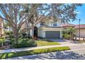 Two-story home featuring a well-maintained lawn, gray facade, tile roof, and attached two-car garage at 23138 Copperleaf Dr, Venice, FL 34293