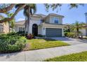 Two-story home featuring a well-maintained lawn, gray facade, tile roof, and attached two-car garage at 23138 Copperleaf Dr, Venice, FL 34293