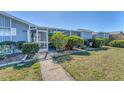 Inviting condo exterior featuring a screened porch, manicured lawn, and well-maintained landscaping at 3300 Loveland Blvd # 1201, Punta Gorda, FL 33980