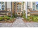 Elegant condo entrance featuring a fountain, brick pathway, palm trees, and manicured landscaping at 385 N Point Rd # 404, Osprey, FL 34229