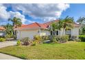 This single-story home features a red tile roof, a two-car garage, and beautifully maintained landscaping at 446 Pinewood Lake Dr, Venice, FL 34285