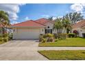 Charming single-story home with a red tile roof, a two-car garage, and beautifully maintained landscaping at 446 Pinewood Lake Dr, Venice, FL 34285