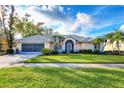 Well-maintained single-Gathering home featuring lush landscaping and a spacious front lawn at 5051 Greenway Dr, North Port, FL 34287