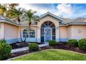 Welcoming front entrance with arched doorway, complemented by beautiful landscaping at 5051 Greenway Dr, North Port, FL 34287