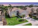 Beautiful single-story home with a well-manicured lawn, palm trees and a view of the golf course at 560 Misty Pine Dr, Venice, FL 34292