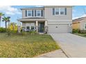 Two-story home features a neutral exterior, blue shutters, a two-car garage, and a charming front porch at 5767 Woodland Sage Dr, Sarasota, FL 34238
