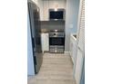 Modern kitchen featuring stainless steel appliances and white cabinetry and light-colored tile flooring at 902 Gibbs Rd # 181, Venice, FL 34285