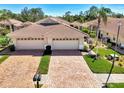 Beautiful villa with a brick driveway and attached two-car garage featuring well-maintained landscaping at 1018 Yosemite Dr, Englewood, FL 34223