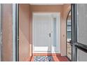 Bright white front door with sidelight, red-tiled porch, and colorful welcome mat at 107 Corot Dr, Nokomis, FL 34275