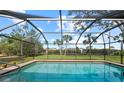 Screened-in outdoor swimming pool with clear water and lush green backyard under a blue sky at 107 Corot Dr, Nokomis, FL 34275