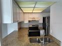 Well-lit kitchen with stainless steel appliances, a range hood, white cabinets and granite countertops at 1190 Longfellow Way # 135C, Sarasota, FL 34243