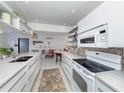 Modern kitchen featuring white cabinets, decorative backsplash, and open shelving at 1200 Yawl Way, Venice, FL 34285