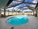 Enclosed pool area featuring a screened-in pool, lounge chairs, and outdoor dining set at 1200 Yawl Way, Venice, FL 34285