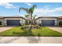 Symmetrical front exterior featuring a brick driveway, well-manicured lawn, and tropical landscaping at 13867 Vadini St, Venice, FL 34293