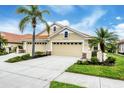 Charming home featuring a three-car garage, lush landscaping, and mature palm trees at 1697 San Silvestro Dr, Venice, FL 34285