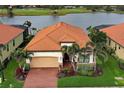 Aerial view of home with a red tile roof, manicured landscaping, and a brick paved driveway at 23415 Waverly Cir, Venice, FL 34293