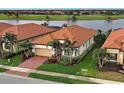 Aerial view of a home with red tile roof, manicured landscaping, and a brick paved driveway at 23415 Waverly Cir, Venice, FL 34293