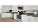 Modern kitchen with stainless steel appliances, granite countertops, and white cabinets at 2572 Averland Loop, North Port, FL 34287