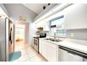 Modern kitchen features white cabinets, stainless steel appliances, tile flooring, and an adjoining bath at 2783 Biscayne Dr, North Port, FL 34287