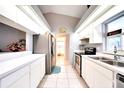 Modern galley kitchen features white cabinets, stainless steel appliances, bright lighting, and vaulted ceiling at 2783 Biscayne Dr, North Port, FL 34287