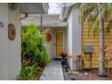 Home entrance featuring mature landscaping, decorative wall hangings, and a yellow front door at 311 Pembroke Dr # 217, Venice, FL 34293