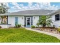 Close-up of the front exterior showing stone accents, well manicured landscaping, and a blue front door at 3286 Meadow Run Cir, Venice, FL 34293