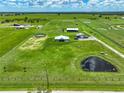 A captivating aerial view showcases the property's amenities, including paddocks, ponds, and outbuildings set against a lush green backdrop at 35960 State Road 70 E, Myakka City, FL 34251