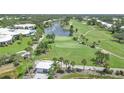 Aerial view of a stunning golf course with a lake and fountain, surrounded by lush greenery and community amenities at 454 Cerromar Rd # 174, Venice, FL 34293