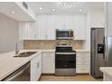 Bright kitchen featuring stainless steel appliances, white cabinets, and a neutral backsplash at 454 Cerromar Rd # 174, Venice, FL 34293