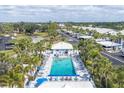 Aerial view of a vibrant pool area with lounge chairs, surrounded by palm trees and community buildings at 454 Cerromar Rd # 174, Venice, FL 34293