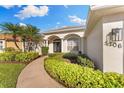 Inviting home entrance with a curved walkway surrounded by lush landscaping and beautiful exterior lighting at 5106 Pine Shadow Ln, North Port, FL 34287