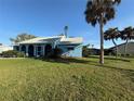 Inviting blue home with arched entry, healthy lawn, and mature palms, creating a picturesque setting at 519 Bellaire Dr, Venice, FL 34293
