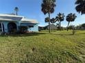 Expansive lawn with mature palms surrounds the light blue home with white trim and large green lawn at 519 Bellaire Dr, Venice, FL 34293