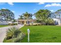 Charming single-story home with a lush green lawn, mature trees, and well-maintained landscaping at 742 Golf Dr, Venice, FL 34285