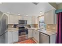 Well-lit kitchen featuring stainless appliances, white cabinets, granite countertops, and a stylish accent rug at 8155 Mossborger Ave, North Port, FL 34287