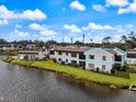 Exterior view of waterfront condo featuring water view, manicured lawn, and community pool in background at 822 Capri Isles Blvd # 210, Venice, FL 34292