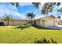 Charming single-story home with a lush green lawn, palm trees, and an attached one car garage at 929 The Rialto, Venice, FL 34285