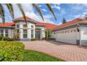 Beautiful home featuring a brick driveway, a three-car garage, a red roof, and well-maintained landscaping at 945 Chickadee Dr, Venice, FL 34285